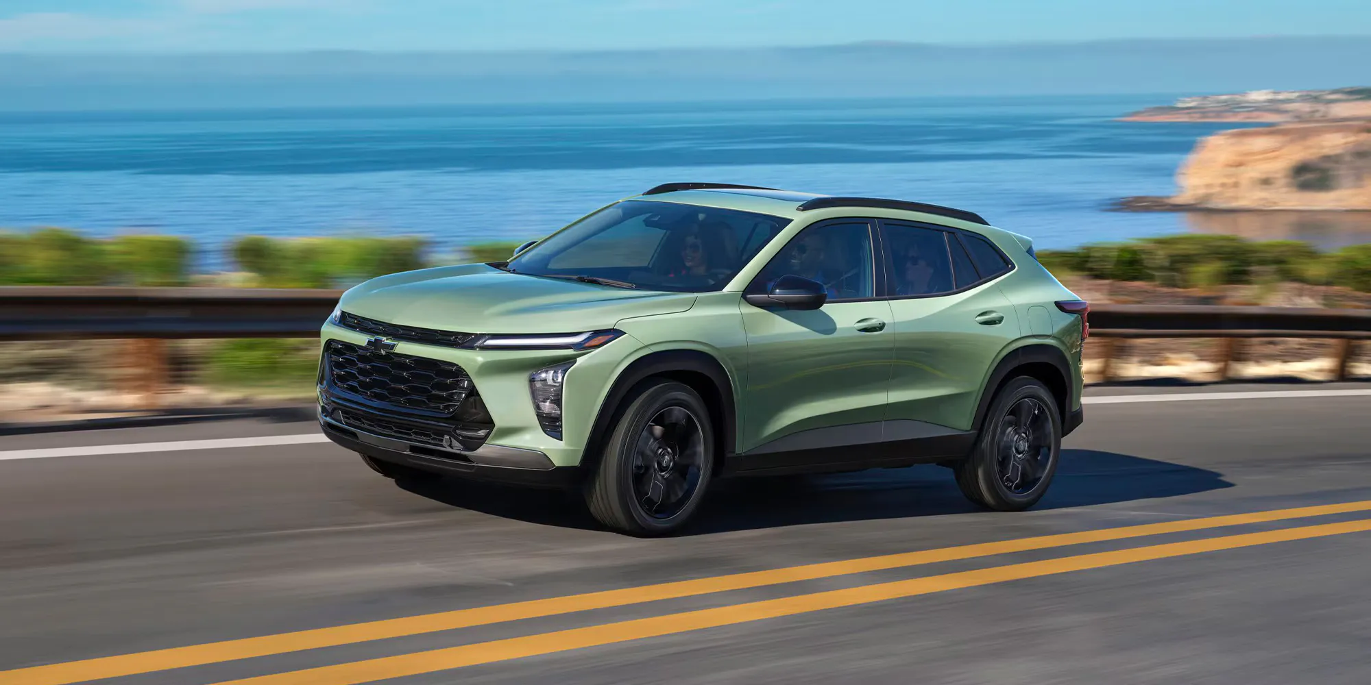 2026 Chevrolet Trax driving on road next to body of water during the daytime